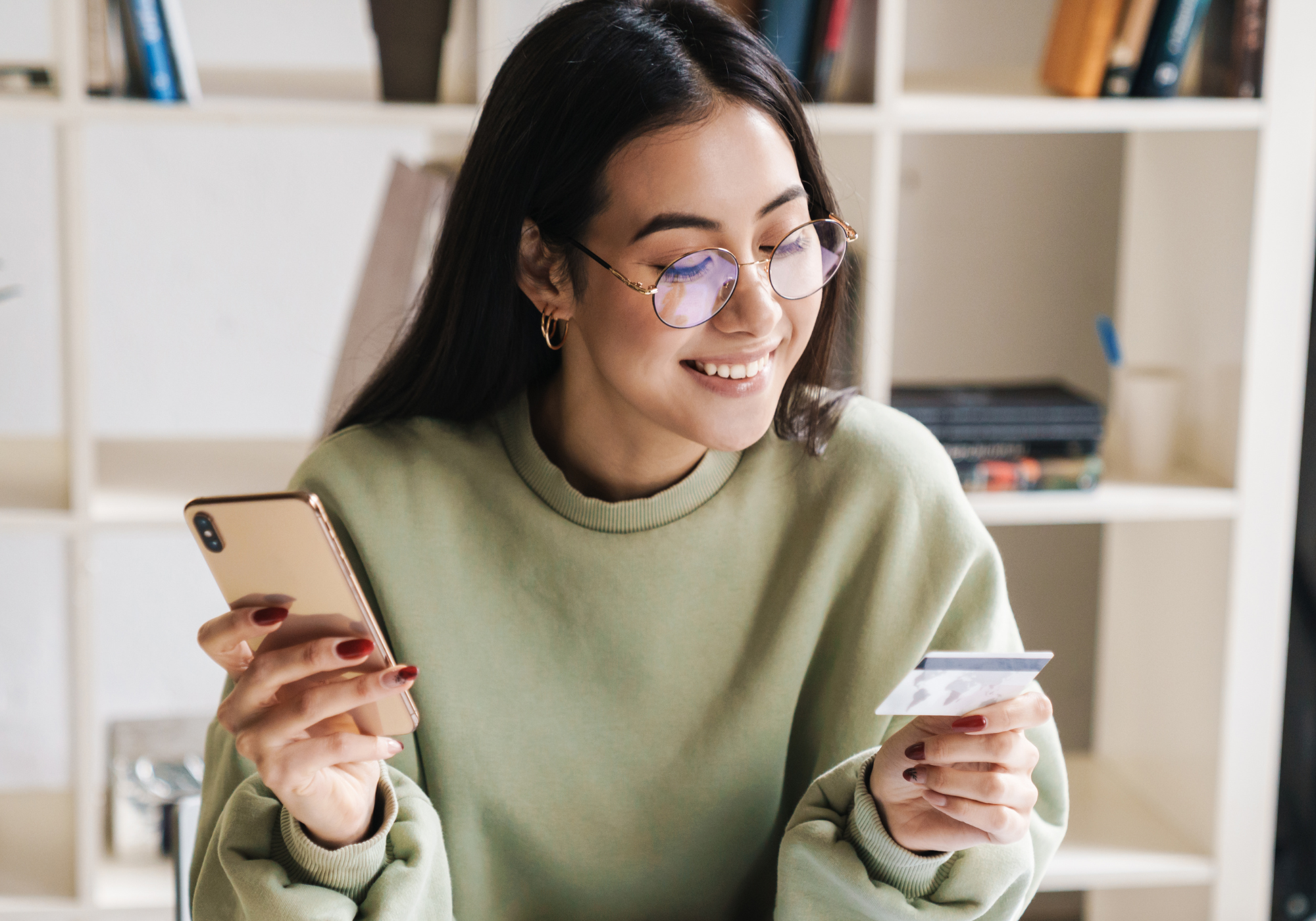 A woman happily using her The Police Credit Union Credit Card to pay for a purchase on her phone. 